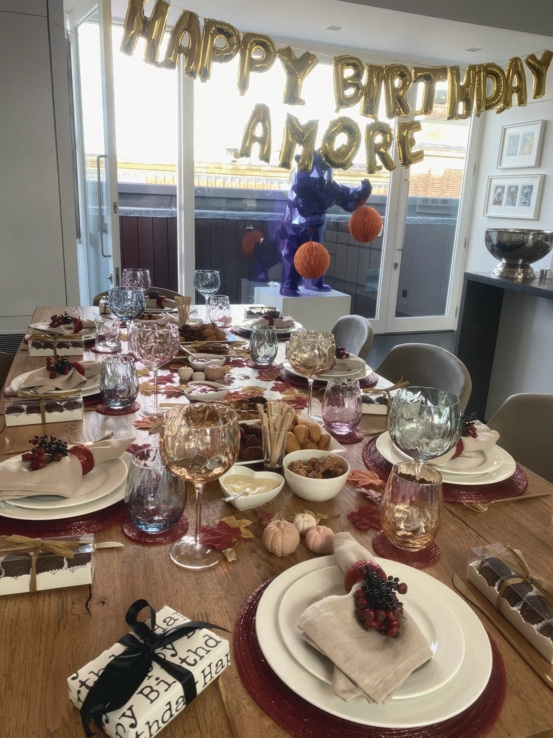 A birthday dinner table set with white plates, red chargers and wine glasses