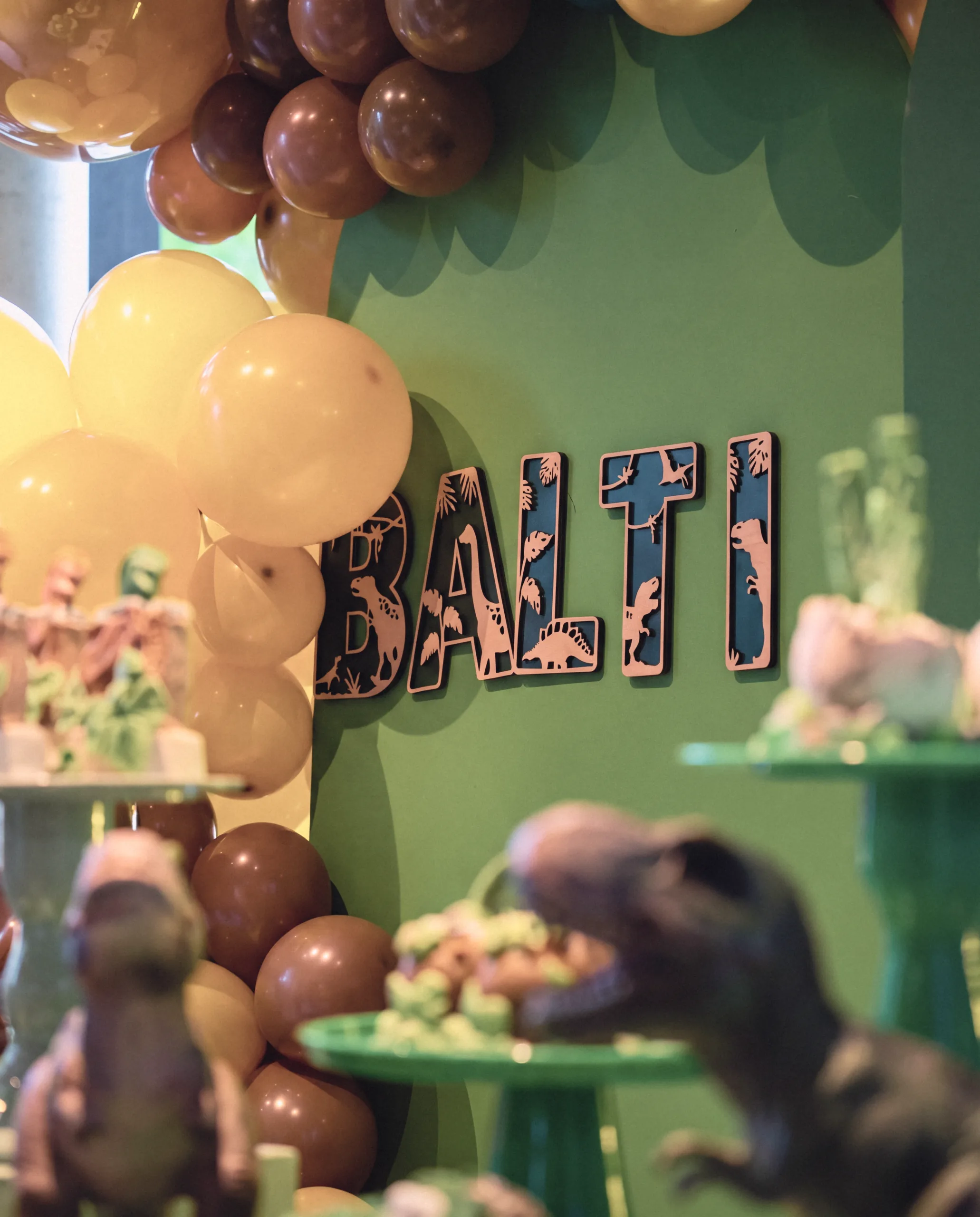 A dessert table under a balloon arch at a dinosaur birthday